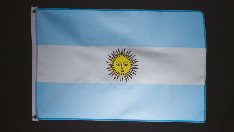 Studioaufnahme-Der-Flagge-Argentiniens,-Die-Vor-Schwarzem-Hintergrund-Herunterfällt