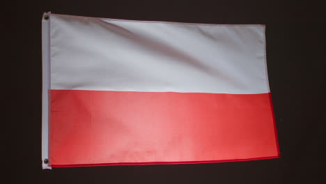 Studioaufnahme-Der-Polnischen-Flagge-Vor-Schwarzem-Hintergrund