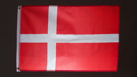 Studioaufnahme-Der-Dänischen-Flagge,-Die-Vor-Schwarzem-Hintergrund-Herunterfällt