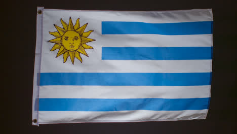 Studioaufnahme-Der-Flagge-Von-Uruguay,-Die-Vor-Schwarzem-Hintergrund-Herunterfällt