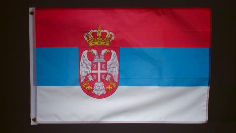 Studioaufnahme-Der-Flagge-Serbiens,-Die-Vor-Schwarzem-Hintergrund-Herunterfällt