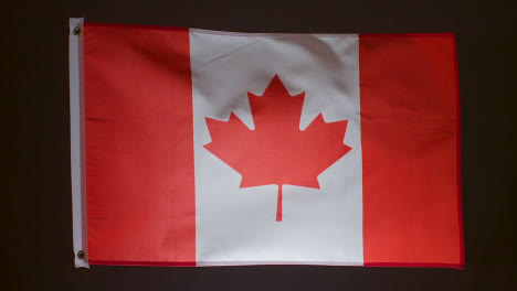 Foto-De-Estudio-De-La-Bandera-De-Canadá-Volando-Sobre-Fondo-Negro