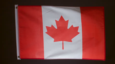 Studioaufnahme-Der-Flagge-Kanadas,-Die-Vor-Schwarzem-Hintergrund-Herunterfällt