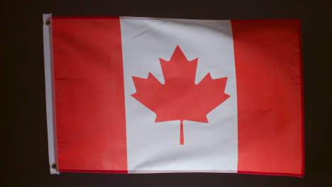 Foto-De-Estudio-De-La-Bandera-De-Canadá-Cayendo-Sobre-Fondo-Negro