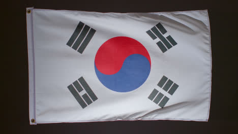 Studioaufnahme-Der-Flagge-Südkoreas,-Die-Vor-Schwarzem-Hintergrund-Herunterfällt