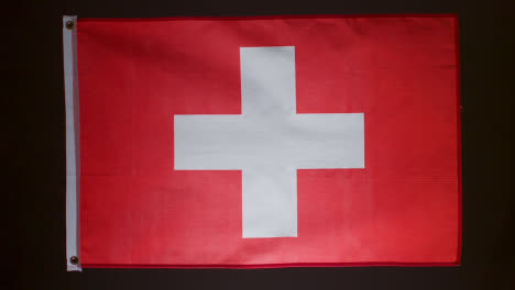 Studioaufnahme-Der-Schweizer-Flagge,-Die-Vor-Schwarzem-Hintergrund-Herunterfällt