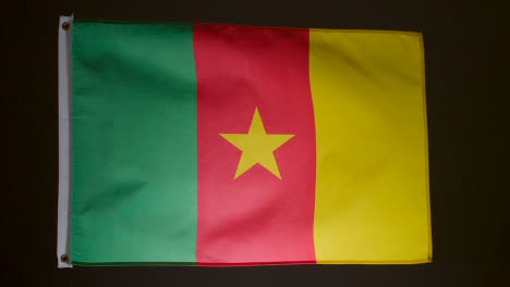 Studio-Shot-Of-Flag-Of-Cameroon-Flying-Against-Black-Background