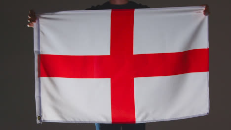Studio-Shot-Of-Anonymous-Person-Or-Sports-Fan-Holding-English-Flag-Of-Saint-George-Against-Black-Background
