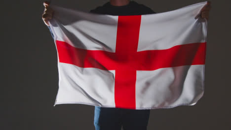 Studio-Shot-Of-Anonymous-Person-Or-Sports-Fan-Waving-English-Flag-Of-Saint-George-Against-Black-Background