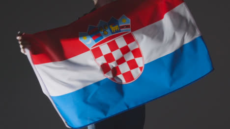 Studio-Shot-Of-Anonymous-Person-Or-Sports-Fan-Waving-Flag-Of-Croatia-Against-Black-Background