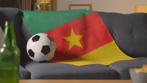 Bandera-De-Camerún-Sobre-Un-Sofá-En-Casa-Con-Fútbol-Listo-Para-El-Partido-En-La-Televisión