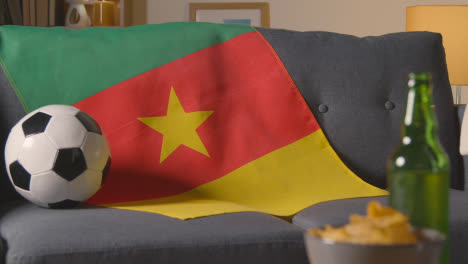 Flagge-Kameruns-über-Sofa-Zu-Hause-Drapiert,-Fußball-Bereit-Für-Spiel-Im-Fernsehen-1