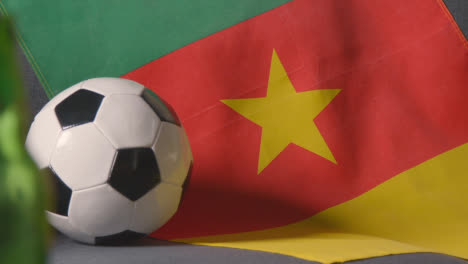 Flag-Of-Cameroon-Draped-Over-Sofa-At-Home-With-Football-Ready-For-Match-On-TV-2