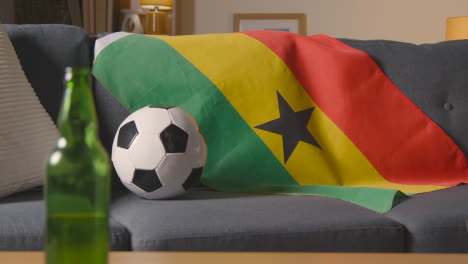 Flagge-Von-Ghana-über-Sofa-Zu-Hause-Drapiert,-Fußball-Bereit-Für-Spiel-Im-Fernsehen-1