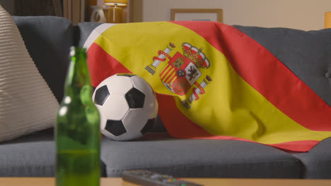 Flagge-Von-Spanien-Drapiert-über-Dem-Sofa-Zu-Hause-Mit-Fußball-Bereit-Für-Das-Spiel-Im-Fernsehen
