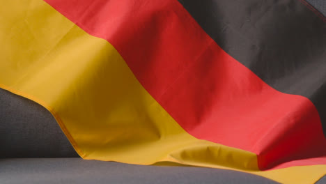 Nahaufnahme-Der-Flagge-Deutschlands,-Die-Zu-Hause-über-Dem-Sofa-Drapiert-Ist,-Bereit-Für-Das-Spiel-Im-Fernsehen