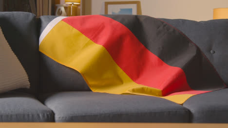 Nahaufnahme-Der-Flagge-Von-Deutschland,-Die-Zu-Hause-über-Dem-Sofa-Drapiert-Ist,-Bereit-Für-Das-Spiel-Im-Tv-1