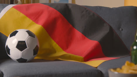 Flagge-Von-Deutschland-Zu-Hause-über-Dem-Sofa-Drapiert,-Fußball-Bereit-Für-Das-Spiel-Im-Tv-1