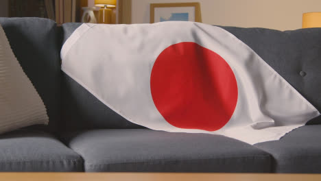 Nahaufnahme-Der-Flagge-Japans,-Die-Zu-Hause-über-Dem-Sofa-Drapiert-Ist,-Bereit-Für-Das-Spiel-Im-Tv-1