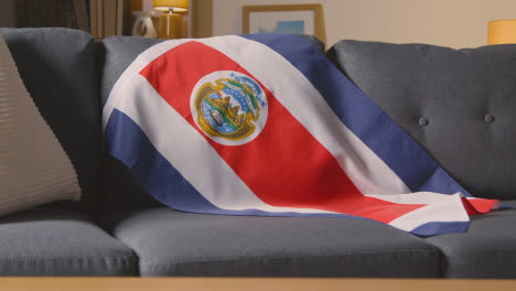 Flagge-Von-Costa-Rica-Zu-Hause-über-Dem-Sofa-Drapiert,-Fußball-Bereit-Für-Das-Spiel-Im-Fernsehen