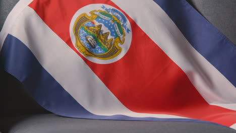 Nahaufnahme-Der-Flagge-Von-Costa-Rica,-Die-Zu-Hause-über-Dem-Sofa-Drapiert-Ist,-Bereit-Für-Das-Spiel-Im-Fernsehen