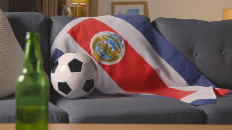 Flagge-Von-Costa-Rica-Zu-Hause-über-Sofa-Drapiert,-Fußball-Bereit-Für-Spiel-Auf-Tv-1