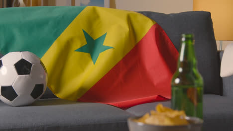 Flag-Of-Senegal-Draped-Over-Sofa-At-Home-With-Football-Ready-For-Match-On-TV-1