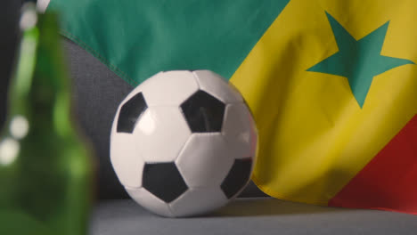 Flagge-Von-Senegal-über-Dem-Sofa-Zu-Hause-Mit-Fußball-Bereit-Für-Das-Spiel-Im-Tv-2