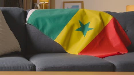 Flag-Of-Senegal-Draped-Over-Sofa-At-Home-Ready-For-Match-On-TV