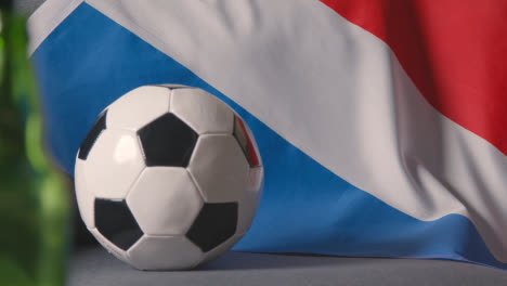 Flag-Of-Holland-Draped-Over-Sofa-At-Home-With-Football-Ready-For-Match-On-TV-2