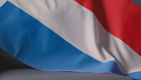 Nahaufnahme-Der-Holländischen-Flagge,-Die-Zu-Hause-über-Dem-Sofa-Drapiert-Ist,-Mit-Fußball,-Der-Für-Das-Spiel-Im-Fernsehen-Bereit-Ist