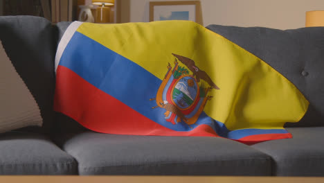 Nahaufnahme-Der-Flagge-Von-Ecuador,-Die-Zu-Hause-über-Dem-Sofa-Drapiert-Ist,-Mit-Dem-Fußball,-Der-Für-Das-Spiel-Im-Tv-1-Bereit-Ist