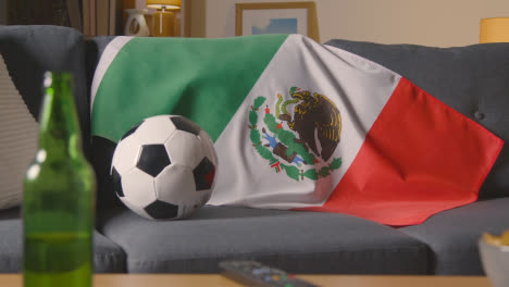 Flagge-Von-Mexiko-über-Sofa-Zu-Hause-Drapiert-Mit-Fußball-Bereit-Für-Spiel-Im-Fernsehen