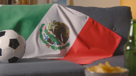 Flagge-Von-Mexiko-über-Dem-Sofa-Zu-Hause-Mit-Fußball-Bereit-Für-Das-Spiel-Im-Tv-1
