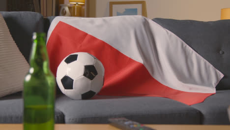 Flagge-Von-Polen-Drapiert-über-Dem-Sofa-Zu-Hause-Mit-Fußball-Bereit-Für-Das-Spiel-Im-Fernsehen