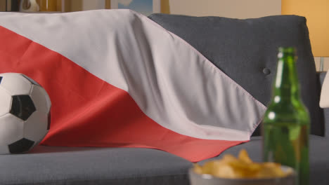 Flag-Of-Poland-Draped-Over-Sofa-At-Home-With-Football-Ready-For-Match-On-TV-1