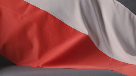 Nahaufnahme-Der-Flagge-Von-Polen,-Die-Zu-Hause-über-Dem-Sofa-Drapiert-Ist,-Mit-Dem-Fußball,-Der-Für-Das-Spiel-Im-Fernsehen-Bereit-Ist