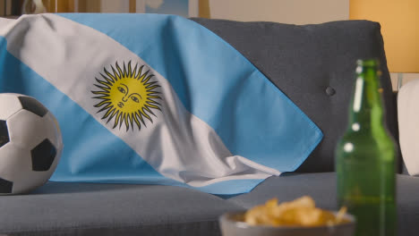 Bandera-De-Argentina-Sobre-Un-Sofá-En-Casa-Con-Fútbol-Listo-Para-El-Partido-En-Tv-1