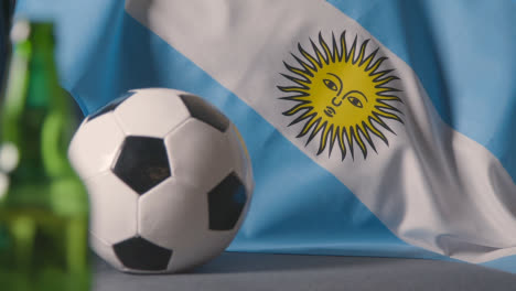 Flagge-Von-Argentinien-über-Dem-Sofa-Zu-Hause-Mit-Fußball-Bereit-Für-Das-Spiel-Im-Tv-2