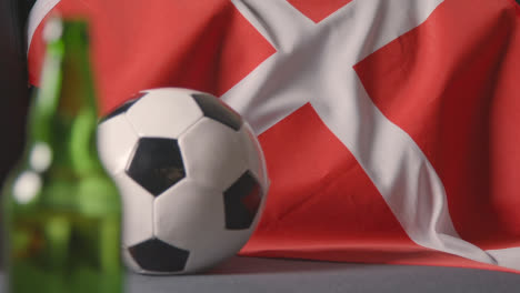 Flagge-Von-Dänemark-Drapiert-über-Dem-Sofa-Zu-Hause-Mit-Fußball-Bereit-Für-Das-Spiel-Im-Tv-1