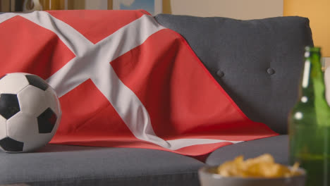 Flag-Of-Denmark-Draped-Over-Sofa-At-Home-With-Football-Ready-For-Match-On-TV-2