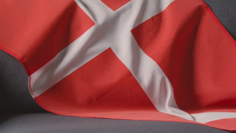 Nahaufnahme-Der-Flagge-Von-Dänemark,-Die-Zu-Hause-über-Dem-Sofa-Drapiert-Ist,-Mit-Dem-Fußball,-Der-Für-Das-Spiel-Im-Fernsehen-Bereit-Ist