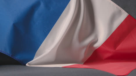 Nahaufnahme-Der-Flagge-Von-Frankreich,-Die-Zu-Hause-über-Dem-Sofa-Drapiert-Ist,-Mit-Dem-Fußball,-Der-Für-Das-Spiel-Im-Fernsehen-Bereit-Ist