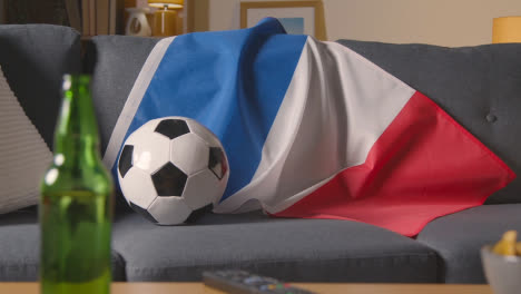 Flagge-Von-Frankreich-Drapiert-über-Dem-Sofa-Zu-Hause-Mit-Fußball-Bereit-Für-Das-Spiel-Im-Fernsehen
