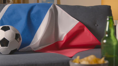 Flag-Of-France-Draped-Over-Sofa-At-Home-With-Football-Ready-For-Match-On-TV-1