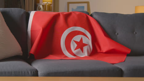 Flag-Of-Tunisia-Draped-Over-Sofa-At-Home-Ready-For-Match-On-TV