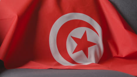 Close-Up-Of-Flag-Of-Tunisia-Draped-Over-Sofa-At-Home-Ready-For-Match-On-TV