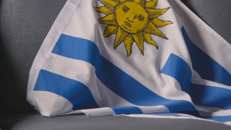 Close-Up-Of-Flag-Of-Uruguay-Draped-Over-Sofa-At-Home-Ready-For-Match-On-TV