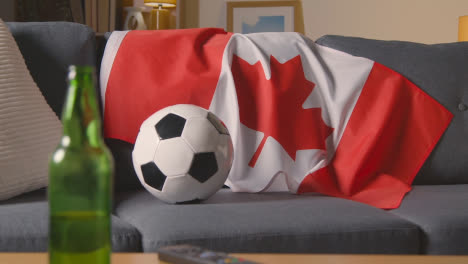 Bandera-De-Canadá-Sobre-Un-Sofá-En-Casa-Con-Fútbol-Listo-Para-El-Partido-En-La-Televisión