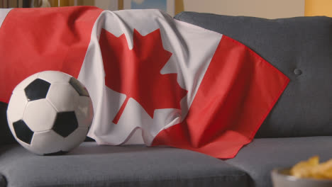 Bandera-De-Canadá-Sobre-Un-Sofá-En-Casa-Con-Fútbol-Listo-Para-El-Partido-En-Tv-1